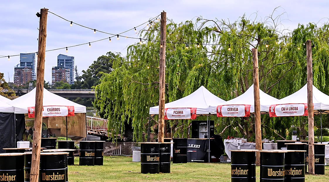 Festival gastronómico con gazebos blancos, postes de madera y guirnaldas de luces
